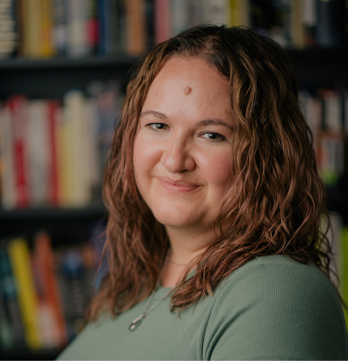 Marisa smiling at the camera in front of bookshelf